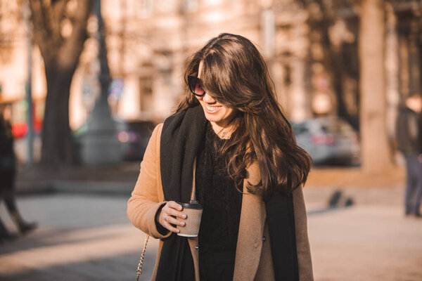 portrait of stylish gorgeous woman in coat outdoors drinking coffee to go copy space