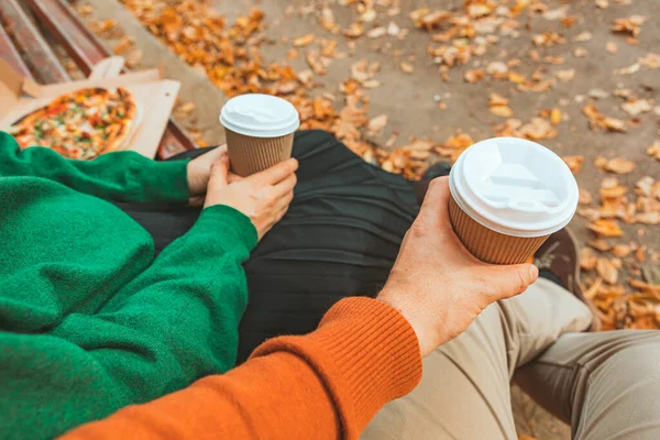 couple hands close-up holding mug with coffee to go. autumn warm day