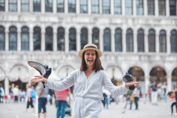 鹿の帽子をかぶった白い服を着た女性がヴィースシティ広場でハトと遊んでいます — ストック写真
