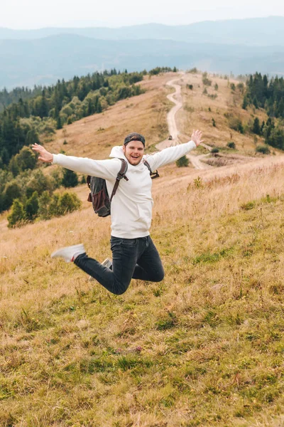 Homme avec sac à dos heureux saut sur le pic sur le mont — Photo