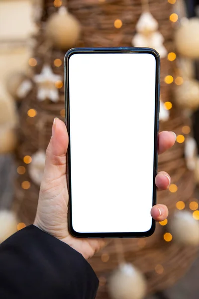 Γυναίκα Χέρι Κρατώντας Τηλέφωνο Λευκό Οθόνη Χριστουγεννιάτικο Δέντρο Στο Φόντο — Φωτογραφία Αρχείου