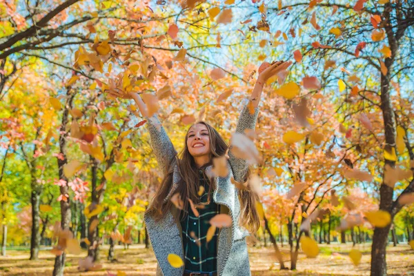 年轻漂亮的女人在城市公园玩黄色的秋叶 — 图库照片