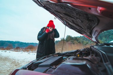 Kadın otomobil motoru yol yardımı kavramına bakıyor.