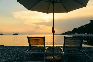 Güneş pansiyonları ve şemsiyeli deniz sahili manzarası. Boşluğu kopyala