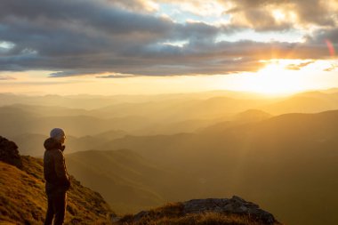 Dağların tepesinde gün batımını seyreden adamın silueti. yürüyüş kavramı