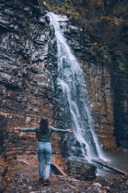Şelale fotokopi alanına bakan günlük elbiseli bir kadın.