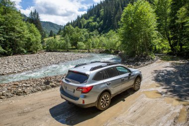 Nehir kenarındaki dağlarda bir arazi aracı. Yolculuk konsepti. off road