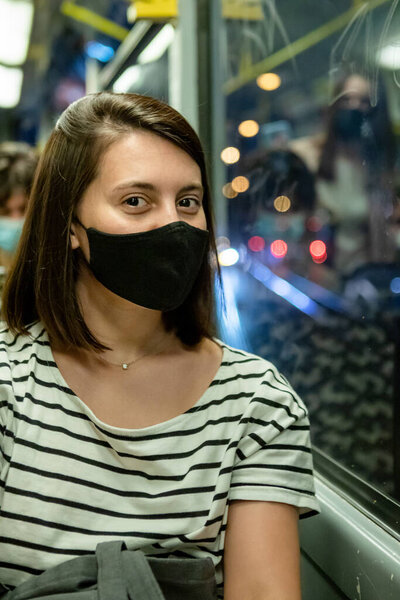 молодая красивая женщина в черной медицинской маске в городском трамвае. covid