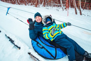 Baba ve oğlu kar tüpünde. Tepeye çek. Kış zamanı