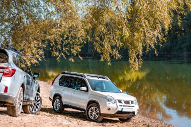 Sonbahar nehri sahiline park edilmiş iki araba. Boşluğu kopyala