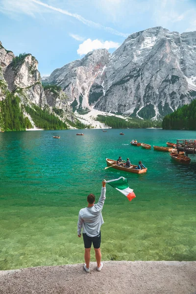 man with italian flag at beach of Braies lake in Dolomites mountains. copy space. summer vacation