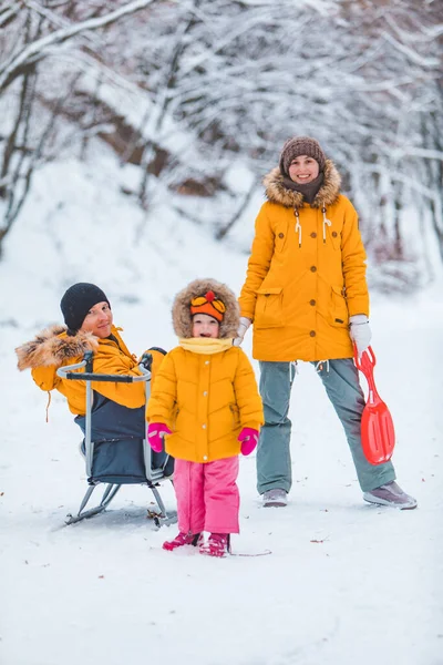年轻的家庭在户外白雪蒙蒙的冬日里一起玩耍 黄色的外套 — 图库照片