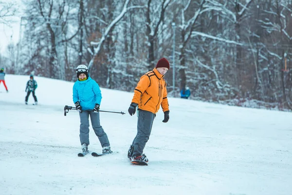 Άντρας Κάνει Σνόουμπορντ Και Γυναίκα Σκι Στο Λόφο Χειμερινές Δραστηριότητες — Φωτογραφία Αρχείου