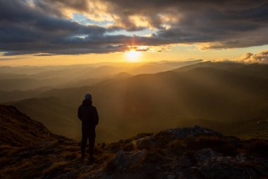 Dağların tepesinde gün batımını seyreden adamın silueti. yürüyüş kavramı