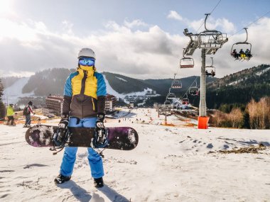 Snowboard kış tatili aktiviteleriyle kayak merkezindeki kadın.