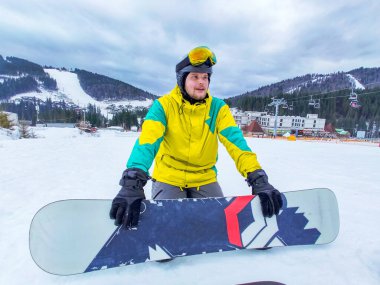Snowboard 'lu bir adam Kar Tepesi Spor aktivitelerinde oturuyor