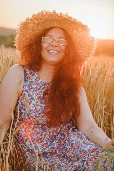 beautiful mature woman in sundress at wheat field on sunset copy space