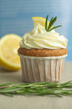 Peynir kreması ile güzel ev yapımı tatlılar fırın mutfağı limon cupcakes, limon dilim, keten masa örtüsü, seçici odak, yakın çekim, kopya alanı, üstten, kafe, ev mavi arka planda biberiye dalı.