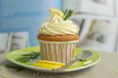 Peynir kreması ile kaşık la tabakta creemy ev yapımı güzel limon cupcake, lor, lezzet, limon dilimleri, sackcloth mavi yemek kitabı arka plan biberiye dalları, seçici odak, yakın, kopya alanı, bokeh, trend colores