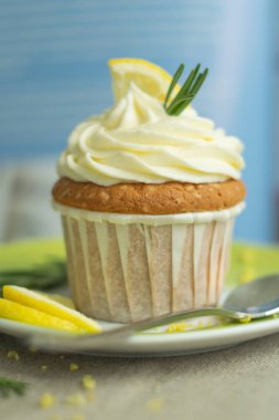 Peynir kreması ile yeşil tabakta güzel lezzetli ev yapımı pasta limon cupcake Makro, lor, limon dilim, keten tekstil mavi arka planda biberiye parçaları, seçici yumuşak odak, yakın, kopya alanı, bokeh, kaşık ve bulanık geri
