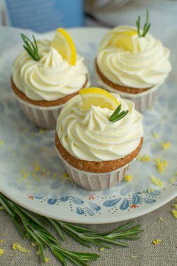 Taze fırın tatlılar tarifi kitap kapak tatlı limon cupcakes peynir krema, limon dilim, çuval bezi de mavi plaka parşömen backgroud yeşil biberiye dalları, seçici odak, yakın, kopya alanı,