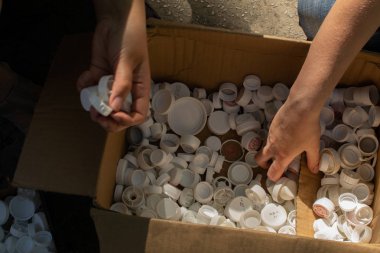 Çevre dostu adam el sıralama ve çöp kutusuna geri dönüşüm kavramı çevre koruma dünya için renkli plastik kapak yeniden koyarak