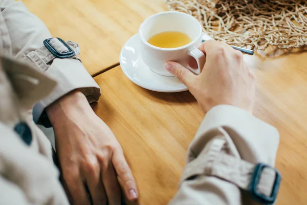 Meeting friends in cafe. The girl drinks tea, coffee in a cafe and touches the cup with her hands, close-up, during meeting with friend