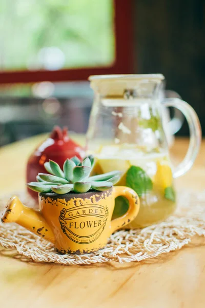 Cozy cafe interior with red teapot, glass jug, succulent in yellow pot, coffee or tea in a restaurant, close-up, at wooden table, during meeting and conversation with friend, background