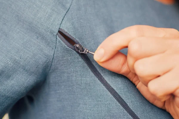 Genç kadın, fermuarını aç. Doğal keten mavisi hemşire bezi. El yapımı elbise, yakın plan, arka plan.