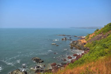 Güzel Goa plaj, kayalık sahil ve yüksek yeşil uçurumdan mavi deniz manzarası, Açık gökyüzü arka plan Hindistan