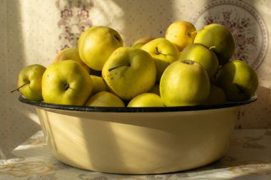 Masadaki tabakta olgun sarı elmalar