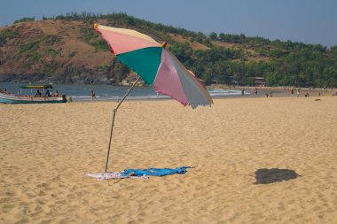 Güneşli bir günde kumsal şemsiyesi, arka planda deniz ve dağ
