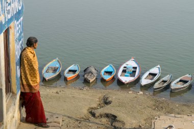Varanasi, Hindistan - Aralık 2016: Tekneler ve kimliği belirsiz yaşlı kadın