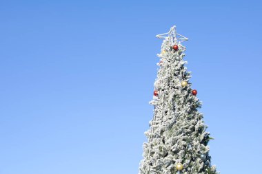 Kışın mavi gökyüzü arka planında süslemeleri olan Noel ağacı. Mutlu Noeller ve fotokopi alanlı mutlu yıllar..