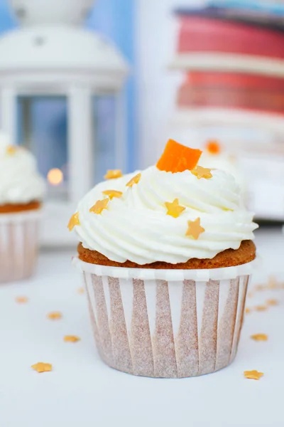 Cupcake met room, sinaasappel gekonfijte vruchten en goudsnoep besprenkeld, lantaarn met licht. Foto voor een menu of een snoepgoed catalogus. — Stockfoto