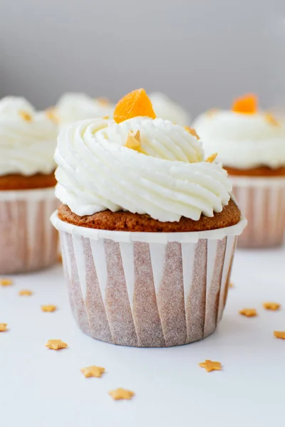 One cupcake with cream, orange candied fruit and gold confectionery sprinkling. Picture for a menu or a confectionery catalog. — Stock Photo, Image