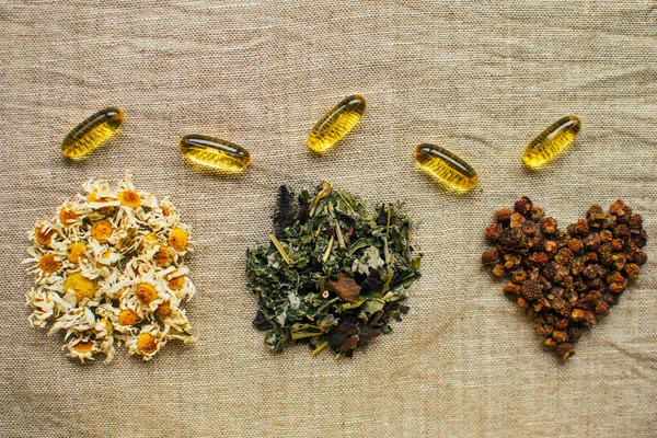 Kuru papatya çiçekleri, balık yağı, saçılmış otlar ve kuru meyveler keten kumaşta kalp şeklinde, alternatif tıp