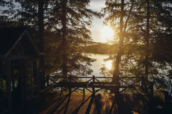 Pôr do sol vista para o lago a partir de uma típica casa de verão com sauna na Finlândia . — Fotografia de Stock