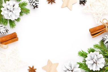 Köknar ağacı dalları, koniler, tarçın ve beyaz arka planda yıldızlar olan bir Noel çerçevesi. Noel düzlüğü metin için boşluk ile yatıyordu.