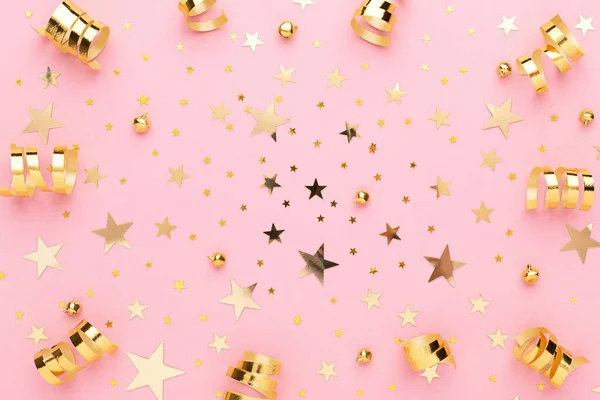 Pink pastel festive flatly. Many sparkling golden confetti and ribbons scattered at pink background. Festive concept.