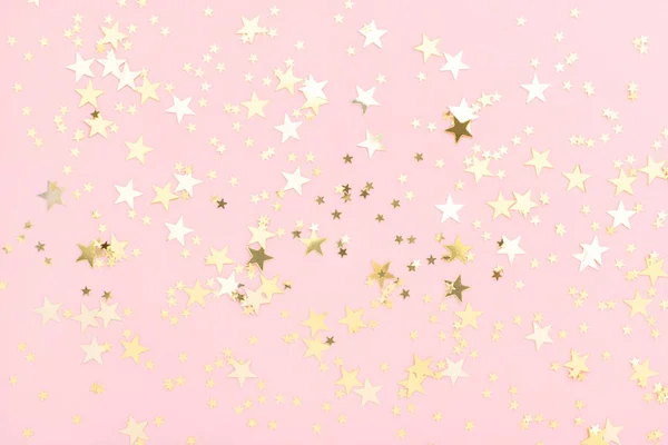 Pink pastel festive background with shining golden confetti in shape of stars. — Stock Photo, Image