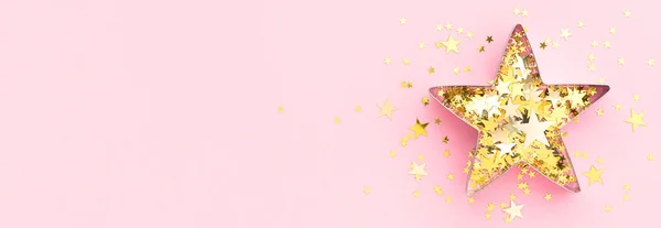 Pink banner.Festive flatly. Star made of cookie form and golden confetti at pastel pink background. Creative decoration concept.