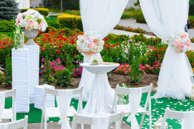 Güzel dekorasyon düğün töreni. Konuklar şenlikli Kemer yol açan çiçeklerle süslenmiş kaldırım tarafındaki beyaz Ahşap sandalyeler