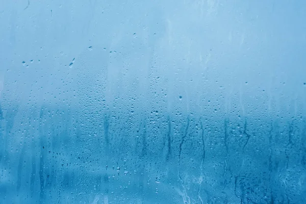 The texture of natural water drops on glass. High humidity indoor. Close-up with condensation