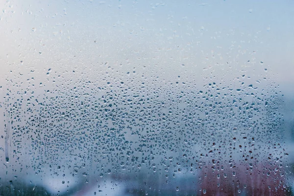 Misted glass background. Strong humidity in wintertime. Water drops from home condensation on a window