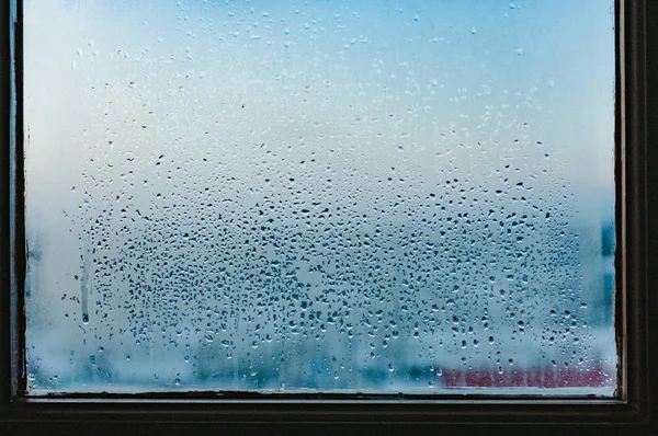 Strong humidity in wintertime. Water drops from home condensation on a window. Misted glass background