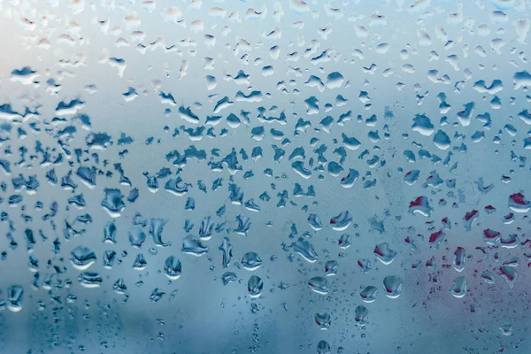 Misted glass background. Strong humidity in wintertime. Water drops from home condensation on a window