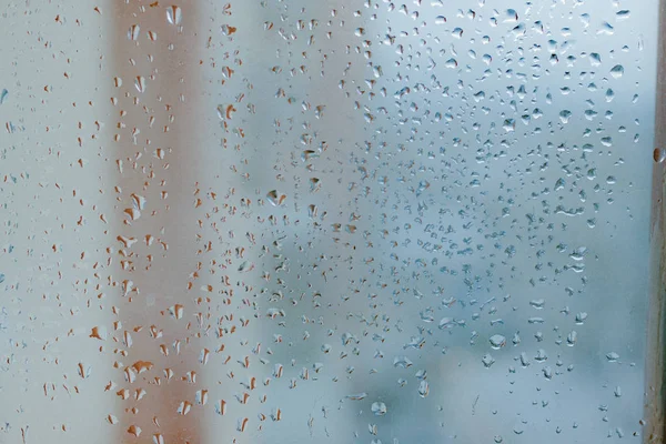 Misted glass background. Strong humidity in wintertime. Water drops from home condensation on a window