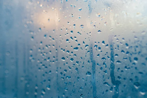Strong humidity in wintertime. Water drops from home condensation on a window. Misted glass background