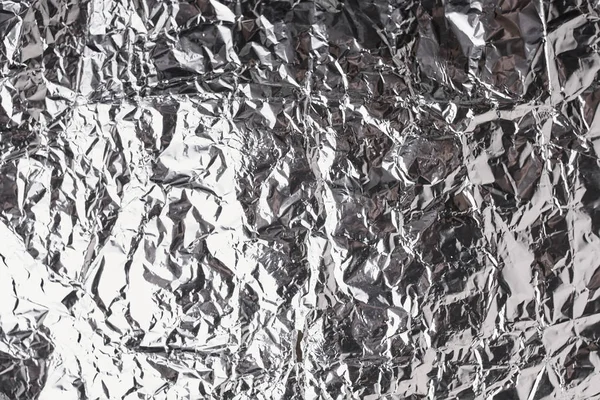 Silver crumpled foil shiny metal texture background wrapping paper for wallpaper decoration element. Grey platinum metallic